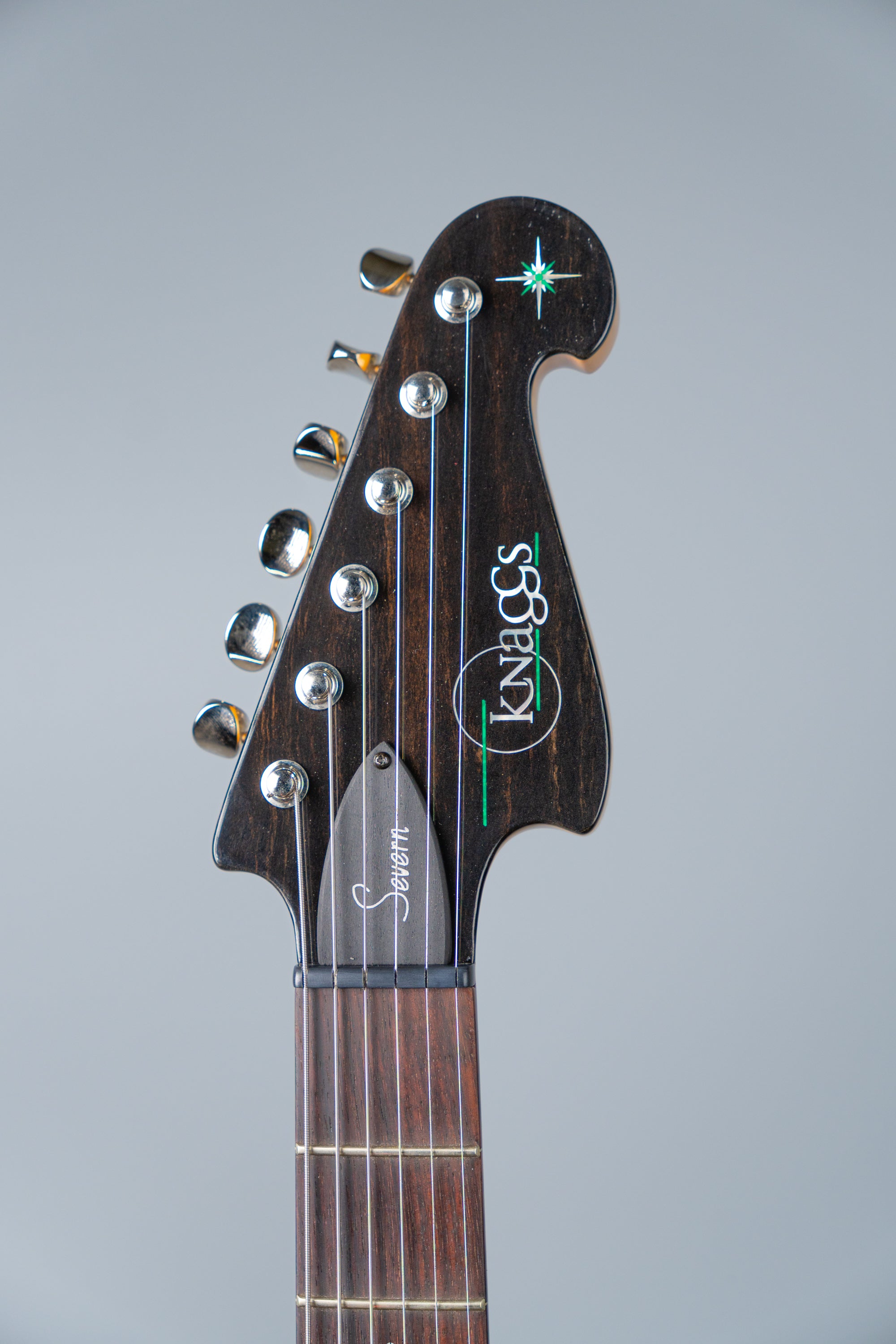 Knaggs Severn electric guitar headstock with Knaggs logo on a gray background