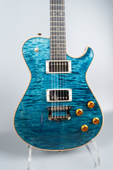 Blue Knaggs Kenai electric guitar on a stand against a light gray background