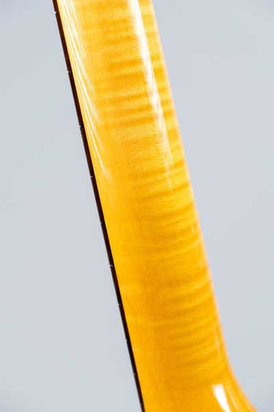 Close-up of a Knaggs Severn electric guitar flamed maple neck on a gray background