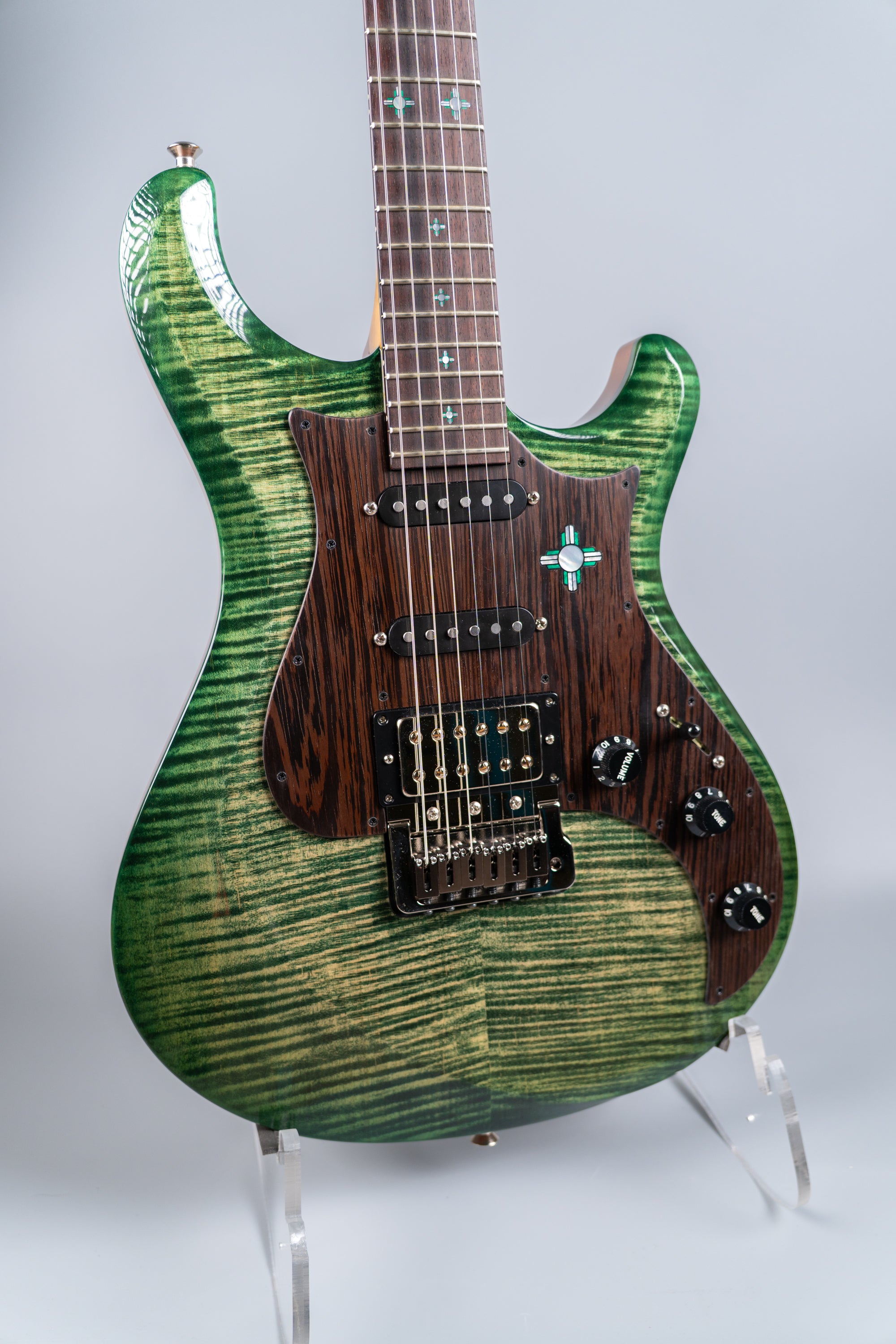 Green electric guitar Knaggs Severn HSS front of a body on a stand against a grey background